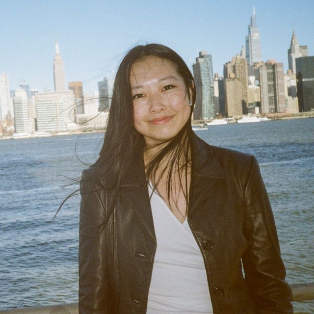 Jenny Zhu on the Greenpoint waterfront, the Midtown Manhattan skyline across the East River behind her